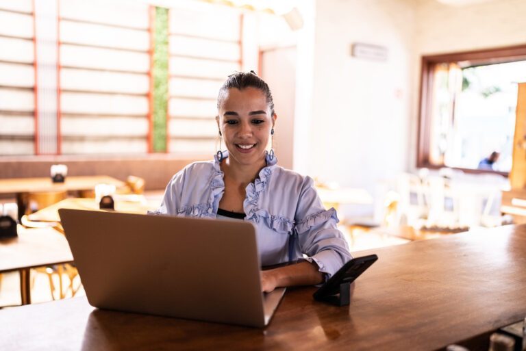 Mid adult woman using the laptop at a bar